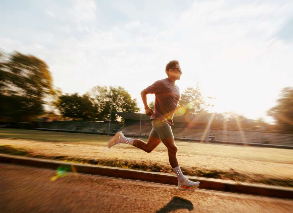Longevity Meaning: Why It Matters in Sports? longevity meaning 1 Runner moving at a steady pace on an outdoor track during golden hour, representing longevity meaning through consistent training and long-term athletic health.